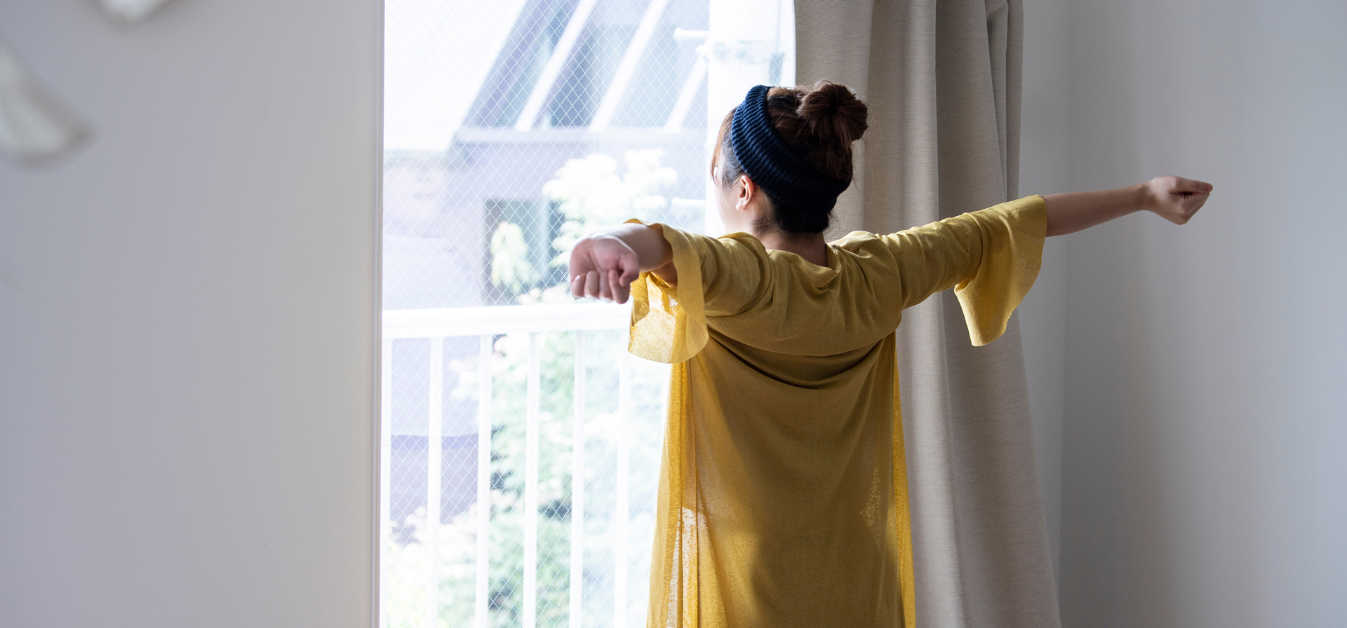 朝窓の前で伸びをしている女性